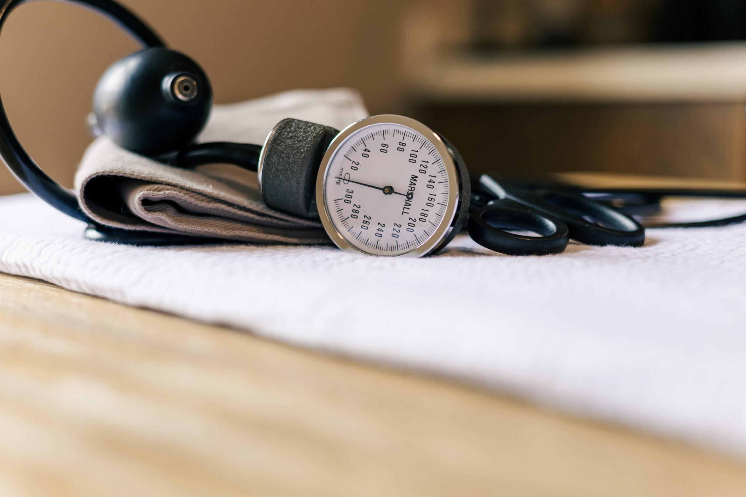 Stethoscope and blood pressure cuff on white linen on a light hard wood table, side view Photo credit: Ryan Kirst