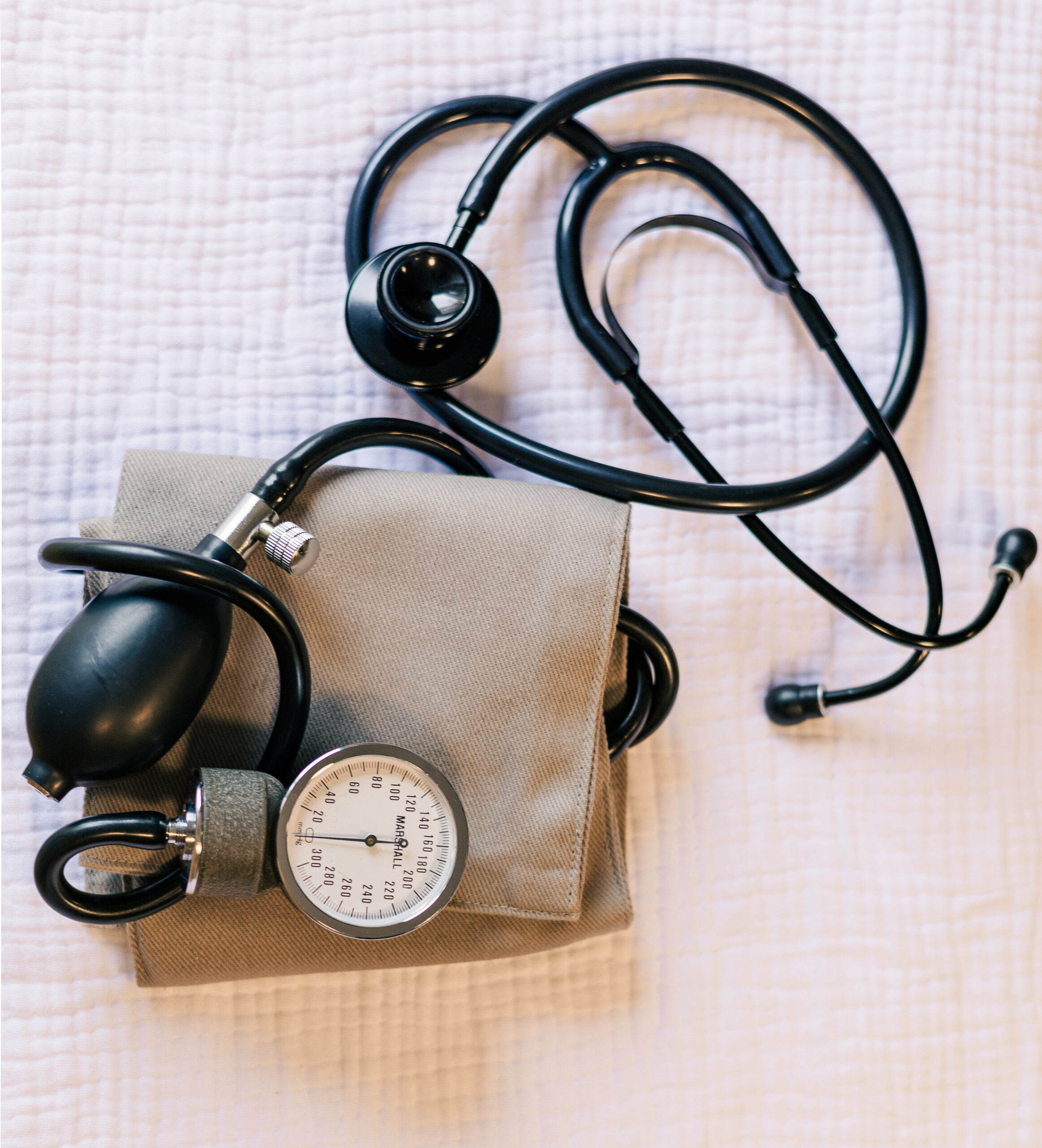 Stethoscope and blood pressure cuff on white linen on a light hard wood table, above view Photo credit: Ryan Kirst