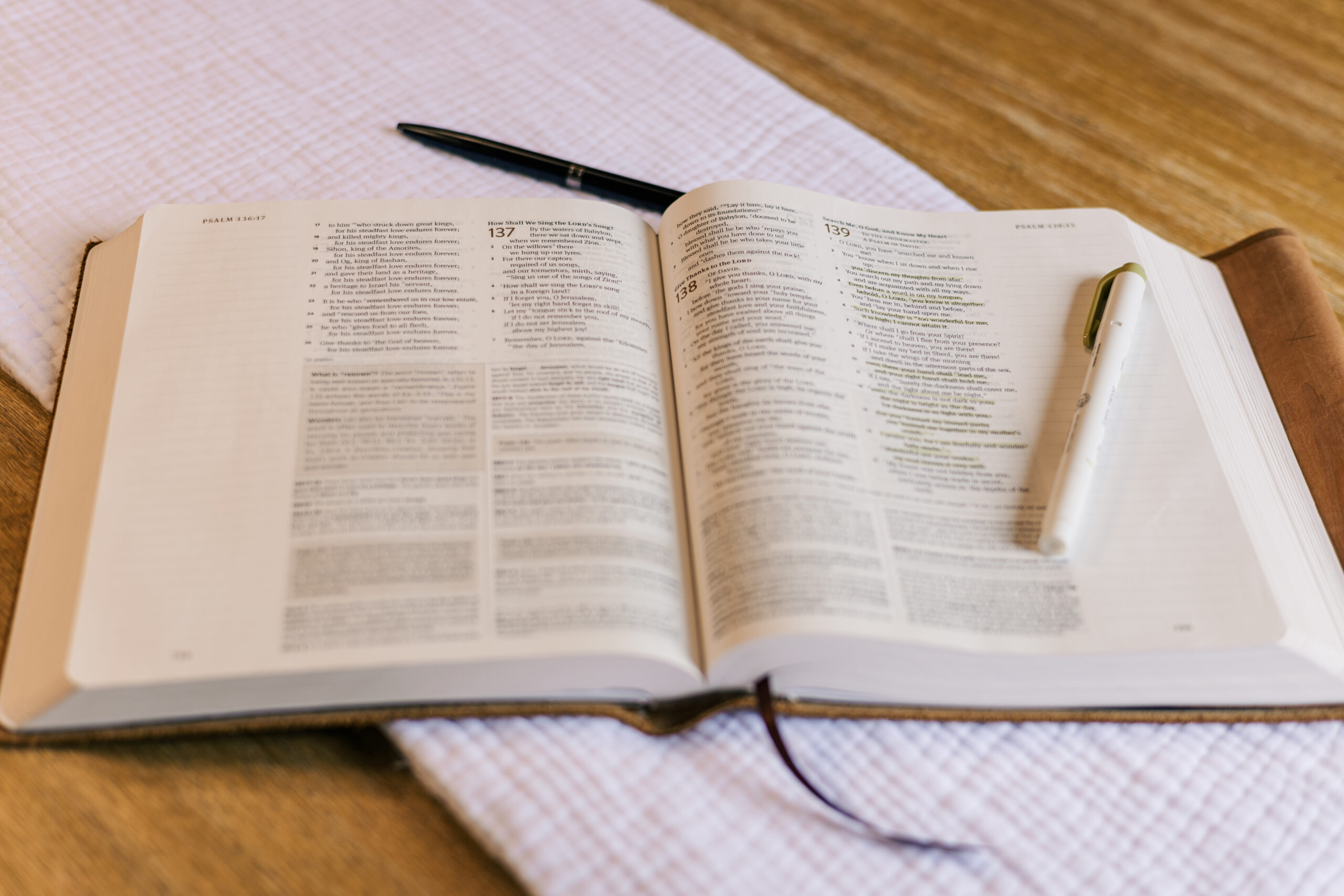 Bible open with pen and highlighter sat on white linen on a light hard wood table Photo credit: Ryan Kirst