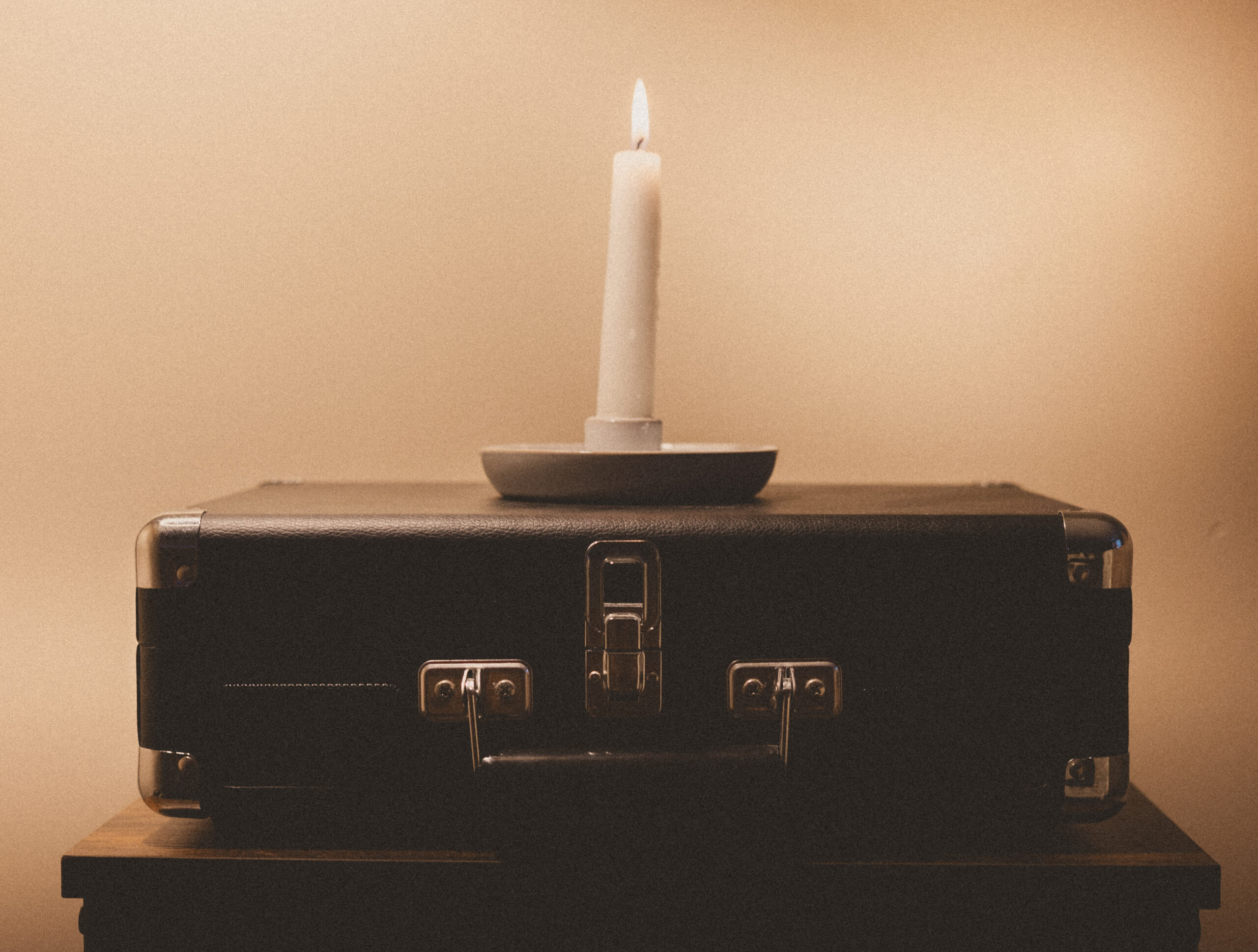 White taper candle lit on top of a black record player Photo credit: Ryan Kirst