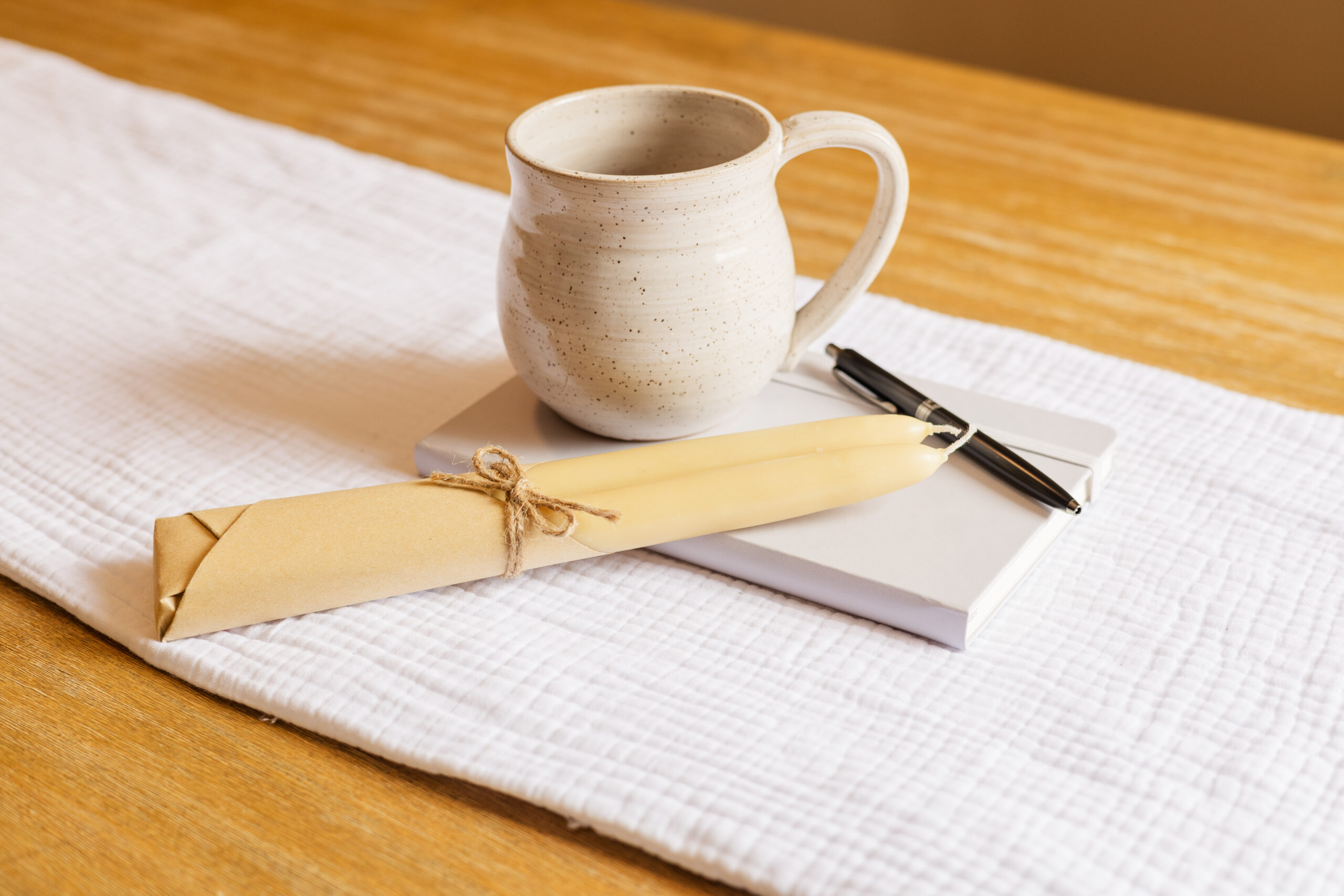 Ceramic mug and beeswax candlesticks sitting on top of purple journal Photo credit: Ryan Kirst