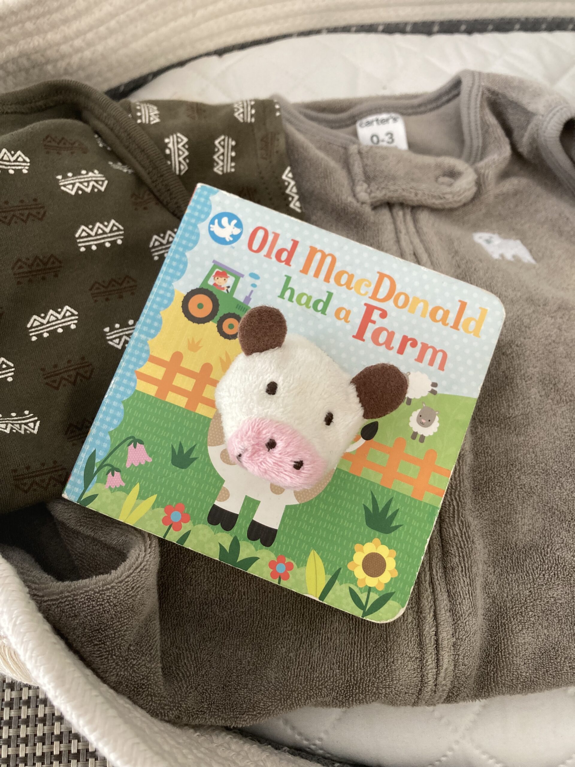 Soft gray Baby onesie with a story book laying on top. Photo credit: Kati Kirst